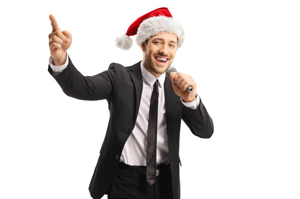 Man wearing a Santa Claus hat singing on a microphone and pointi - Foto, Imagen