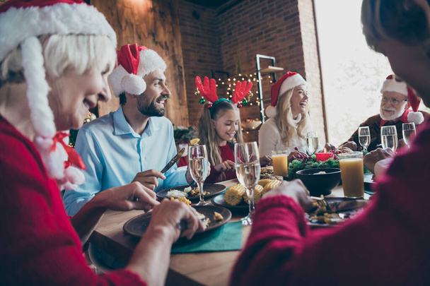 Large family gathering concept man woman small little girl in santa claus hat deer headband sit table with x-mas feast eat speak talk with mature retired relatives in house merry newyear decoration - Foto, afbeelding