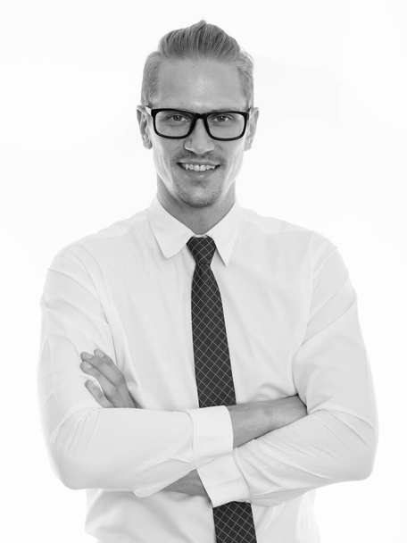 Happy young handsome businessman smiling while wearing eyeglasses with arms crossed - Фото, изображение
