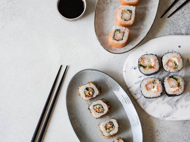 Variedade de rolos de sushi com camarão, salmão, atum servido em prato cerâmico e bordo
. - Foto, Imagem