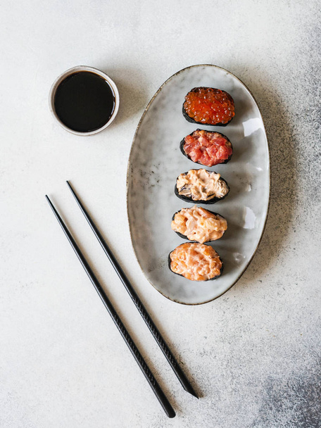 Ποικιλία gunkans με σολομό, γαρίδες, τόνο, μύδια, κόκκινο χαβιάρι σε ένα οβάλ κεραμικό πιάτο. Άνω όψη - Φωτογραφία, εικόνα