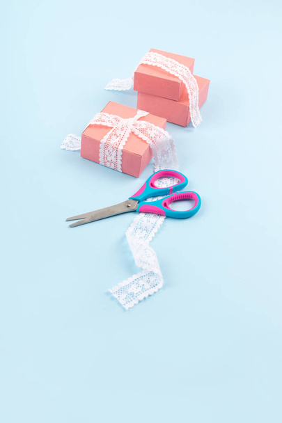 Ροζ κουτιά δώρου με δαντέλα και ψαλίδι σε μπλε φόντο χρώμα. - Φωτογραφία, εικόνα