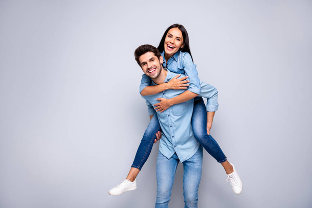 Photo of funny guy and lady holding piggyback playing leisure game rejoicing wear casual jeans clothes isolated grey color background - Фото, изображение