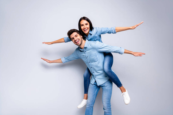 Photo of cool pair in love guy holding lady piggyback pretending airplane flight spread hands like wings wear casual jeans clothes isolated grey color background - Φωτογραφία, εικόνα