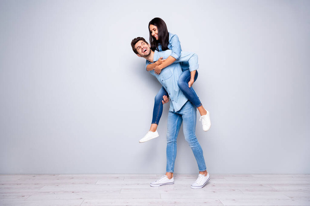 Full size photo of funny guy and lady in piggyback pose walking together to playing yard wear casual jeans clothes isolated grey color background - 写真・画像