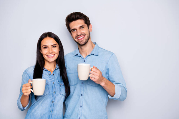 Photo of two amazing colleagues working together spend coffee break holding hot drink cups wear casual jeans clothes isolated grey color background - Foto, imagen