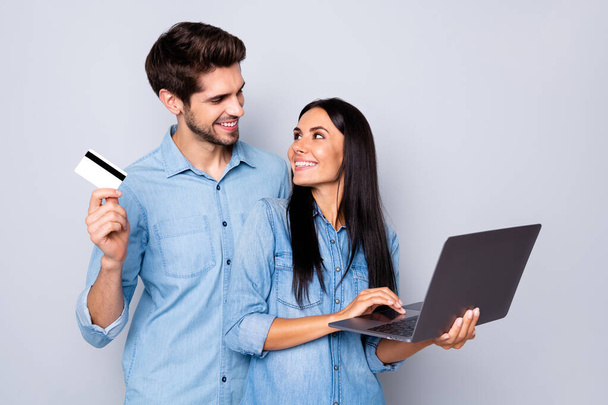 Photo of stylish trendy couple of two people business family with him holding credit card and her laptop developing social media pages isolated grey color background - Foto, Bild