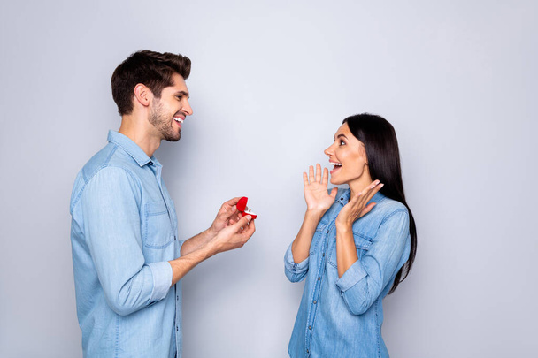 Will you marry me. Photo of gorgeous couple of two people with him proposing to her gifting a ring and her rejoicing before saying yes wearing jeans denim isolated white grey color background - Valokuva, kuva