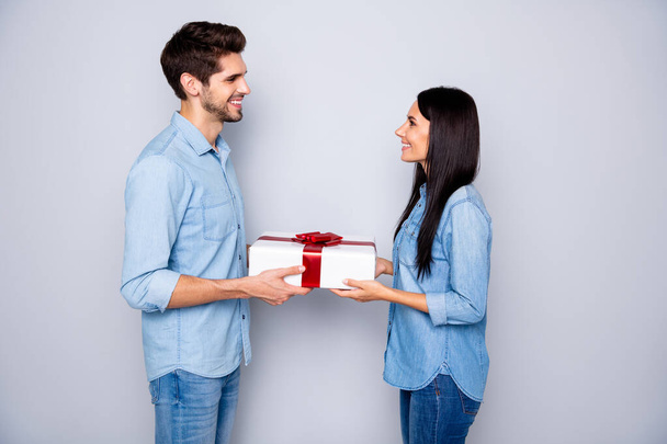 Photo of charming cheerful cute fascinating couple of two people together with him gifting his wife and her thankful to him sincerely for wrapped box wearing denim isolated white grey color background - Zdjęcie, obraz