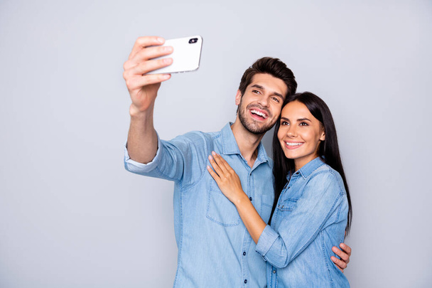 Portrait of nice-looking attractive charming lovely cheerful cheery glad couple holding in hands cell taking making selfie social influencer isolated on light white gray pastel color background - Zdjęcie, obraz