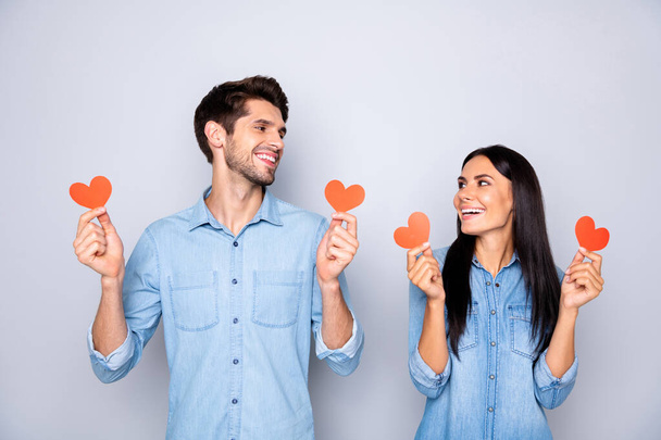 Photo of trendy cute charming lovely sweet couple of two people holding small hearts red looking at each other smilig toothily isolated grey color background - Fotografie, Obrázek