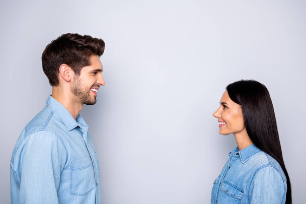 Side profile photo of cheerful charming beautiful couple of two people together setting eye contact speaking with each other wearing jeans denim isolated grey color background - Φωτογραφία, εικόνα