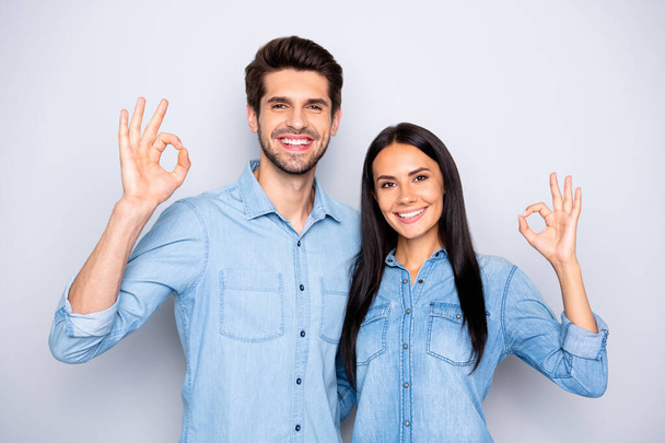 Photo of cheerful charming cute trendy stylish couple of two people standing together wearing jackets of denim showing you ok sign isolated over grey color background - Фото, изображение