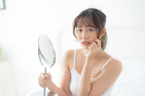 Hermosa joven asiática mujer mirando el espejo con acné problema
 - Foto, imagen