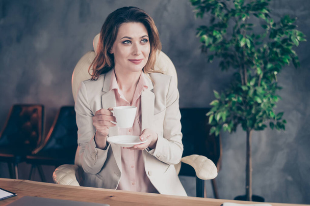 Close-up portrait of her she nice attractive stylish cheerful dreamy mature lady having pause drinking espresso beverage at industrial style interior indoors work place station - Foto, imagen