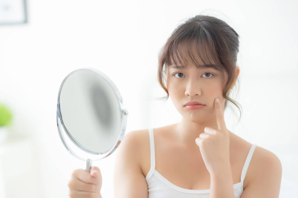 bela jovem ásia mulher olhando o espelho com acne problema
 - Foto, Imagem