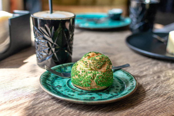 Pistachio eclair, profiterole em esmalte na placa verde na mesa
,  - Foto, Imagem