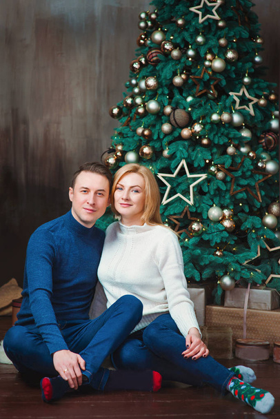 beau, heureux couple caucasien (famille) en jeans et pulls de Noël près de l'arbre de Noël à la maison à l'intérieur. Noël et Nouvel An Concept
 - Photo, image
