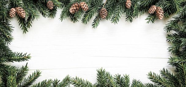 Cadre de Noël de branches de sapin et cônes de pin sur panneau de bois blanc
 - Photo, image