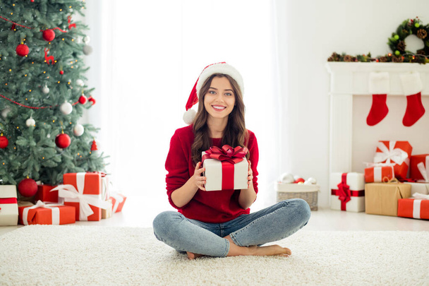 Full length body size photo of charming beautiful attractive pretty sweet girlfriend showing you her wrapped present sitting with crossed legs on floor carpet wearing jeans denim - Foto, Imagem