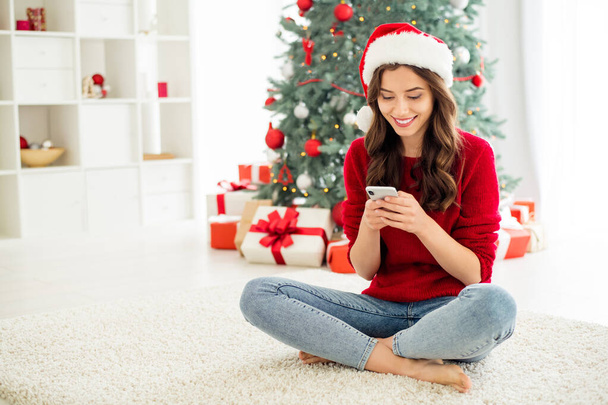 Photo of beautiful attractive fascinating pretty girlfriend chatting with someone by her smart phone while wearing red santa cap hat headwear - Foto, immagini