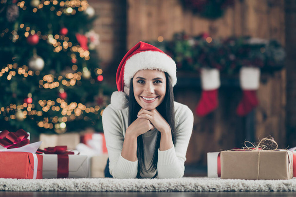 Close up photo of positive cheerful girl lie on floor carpet with cristmas gift boxes enjoying x-mas time jolly party wear white pullover in house with newyear garlands illumination indoors - Foto, immagini