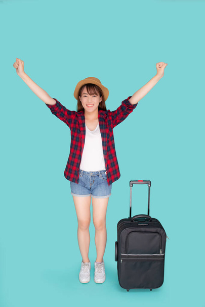 Beautiful young asian woman pulling suitcase isolated on blue ba - Foto, Imagem