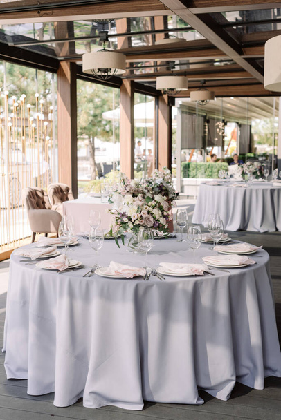 Lujoso diseño de boda para una boda moderna. Mantel gris en el suelo en la mesa redonda
 - Foto, imagen