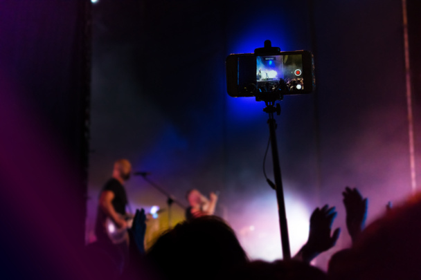 人々は音楽コンサートでスマートフォンのレコードビデオを使用します。群集で  - 写真・画像