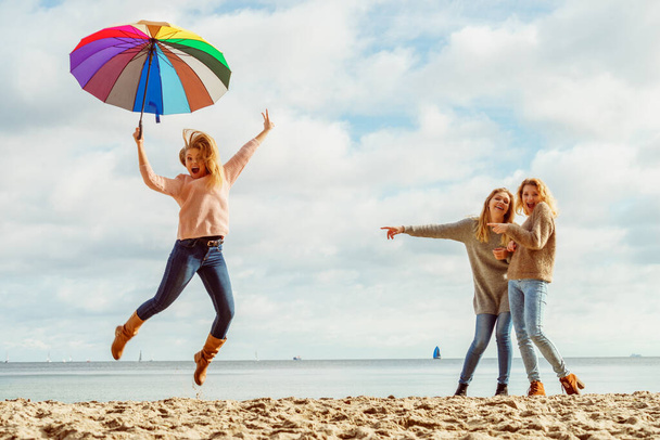 Women jumping with umbrella - Foto, afbeelding