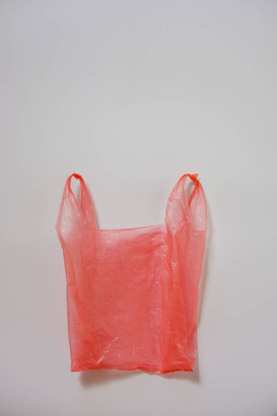 Смятый красный пластиковый пакет на сером
 - Фото, изображение
