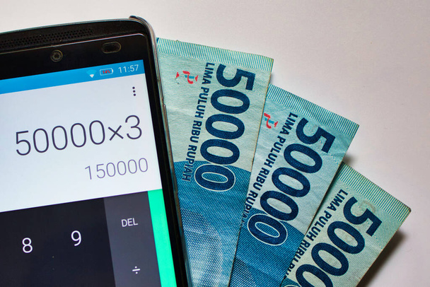 factures de roupie indonésienne et un téléphone mobile exécutant une application de calculatrice
 - Photo, image