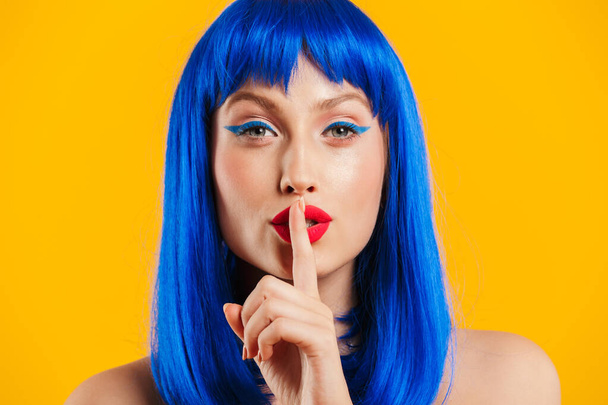 Portrait closeup of seductive cute woman wearing blue wig looking at camera and gesturing silence sign - Foto, imagen