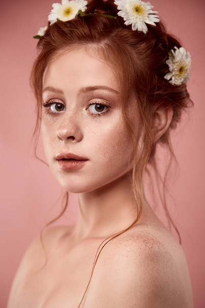 Beautiful positive redheaded girl with a chamomile crown on her  - Fotó, kép