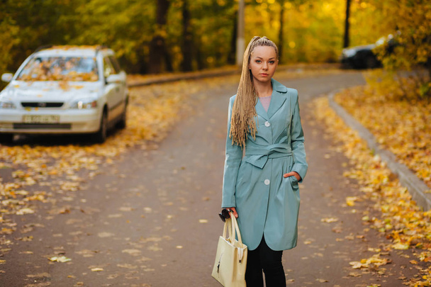 Ragazza un cappotto e una borsa è sulla strada di autunno
 - Foto, immagini
