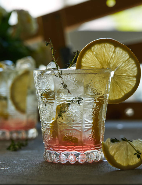 Boisson fraîche au citron et thym dans un verre sur fond gris
 - Photo, image
