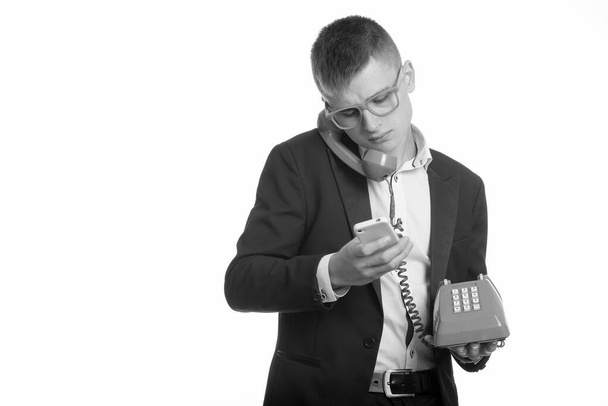 Studio záběr mladého podnikatele mluvit na starý telefon při použití mobilního telefonu - Fotografie, Obrázek