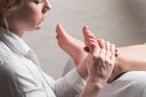 Profesjonalny masażystka daje masaż refleksologiczny kobiecie stóp - Zdjęcie, obraz