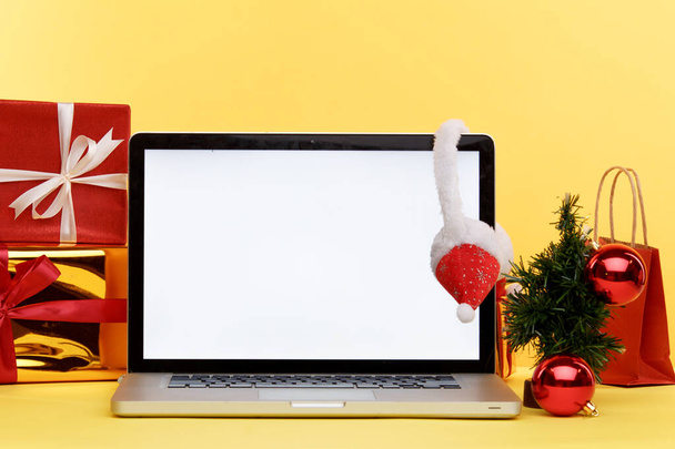 Concept de shopping de Noël en ligne sur l'écran de l'ordinateur portable. Écran blanc sur l'ordinateur et cadeaux avec des sacs en papier près. - Photo, image