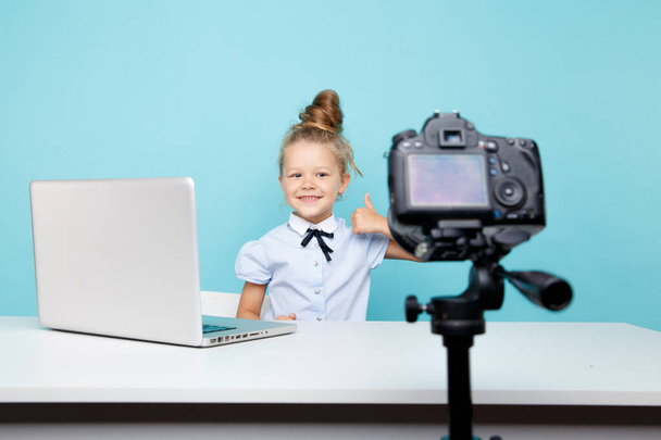 Meisje blogger opname vlog op de camera zit voor de computer in de blauwe studio. - Foto, afbeelding