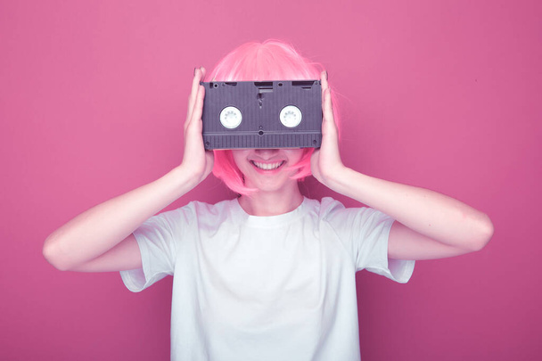 Young girl 90s and VHS cassette on pink - Foto, afbeelding