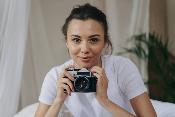 Pretty young woman is holding camera at home - Foto, Imagem