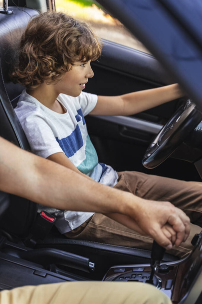 Caucasian man helping little boy to drive car - Фото, зображення
