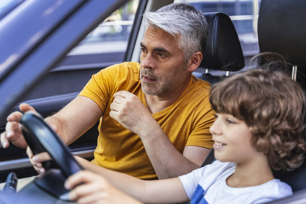 schöner Mann bringt seinem Sohn das Autofahren bei - Foto, Bild