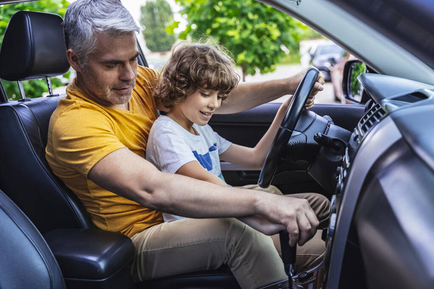 Happy Caucasian man and little boy studying driving vehicle - Foto, afbeelding