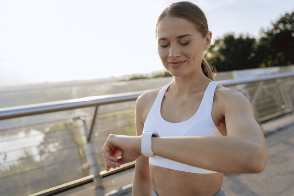 Happy sportive lady looking at smart wrist watch - Foto, imagen