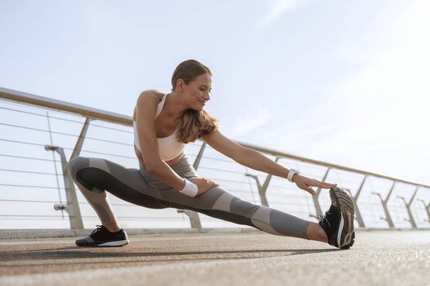 Happy sportive lady doing side legs stretching - Photo, Image
