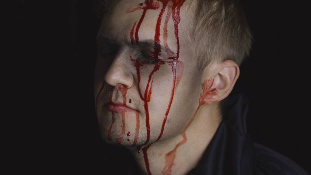 Portret mężczyzny z Halloween. Facet z kapającą krwią na twarzy. Przerażający makijaż. - Zdjęcie, obraz