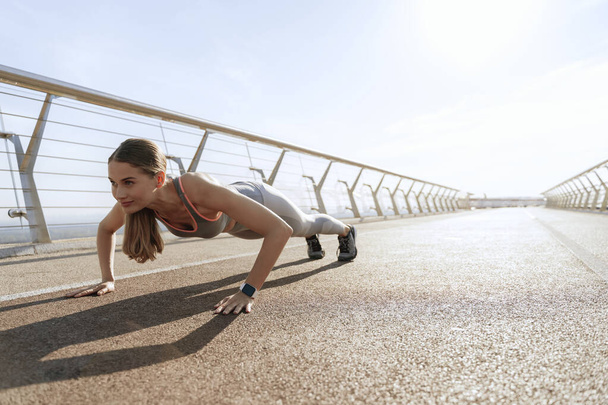 Young happy athletic lady doing plank position - Zdjęcie, obraz
