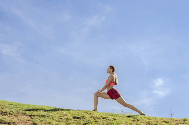 Lady doing pilates workout on green hill - 写真・画像